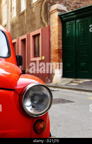 Arancione vecchia FIAT 500 parcheggiato su una strada. Foto Stock