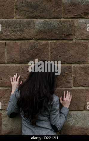 Donna appoggiata contro il muro Foto Stock