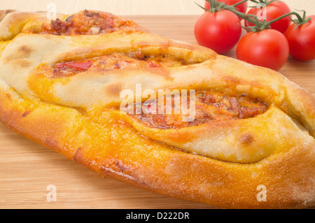 Close-up di un calzone tradizionale pizza su un tagliere di legno Foto Stock