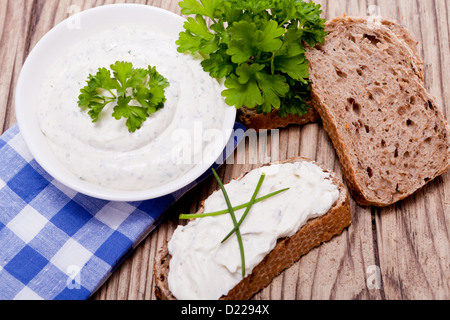 Freschi e saporiti crema a base di erbe il formaggio e il pane sulla tavola di legno Foto Stock