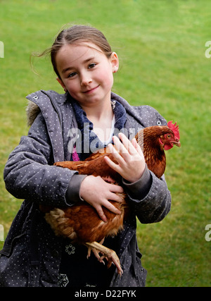 Giovane ragazza sorridente tenendo una gallina in Irlanda rurale Foto Stock