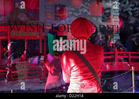 La signora in rosso alla vetrina di un negozio a New York Foto Stock