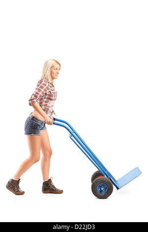 A piena lunghezza Ritratto di un lavoratore di sesso femminile che spingendo un vuoto carrello a mano isolata contro uno sfondo bianco Foto Stock