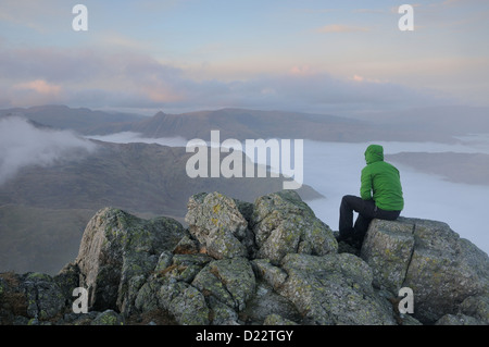 Walker godendo la vista dalla cima del Wetherlam al crepuscolo in Englsh Lake District Foto Stock