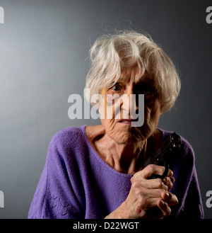 Vendicativo abusato senior donna con un occhio nero e una pistola. Foto Stock