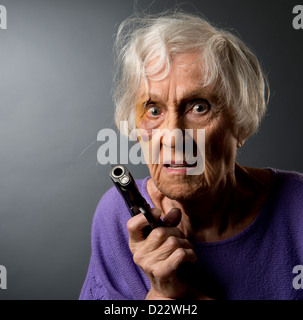 Vendicativo abusato senior donna con un occhio nero e una pistola. Foto Stock