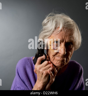 Vendicativo abusato senior donna con un occhio nero e una pistola. Foto Stock