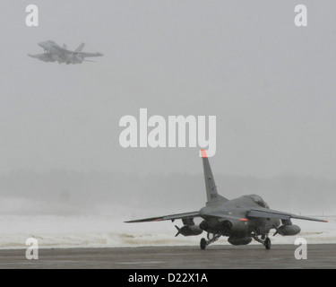 Un EA-18G Growler dell'Electronic Attack Squadron 132 decolla dalla base aerea di Misawa, in Giappone, mentre un Kawasaki T-4 dai taxi della Japan Air Self-Defence Force sulla linea di volo. Misawa è una base militare condivisa tra Stati Uniti e Giappone. Foto Stock