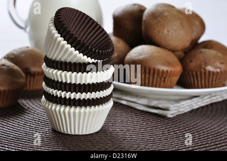 Marrone e bianco cupcake casi con tortini di cioccolato su sfondo scuro Foto Stock