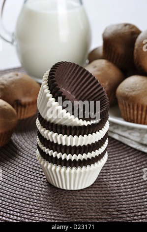 Marrone e bianco cupcake casi con tortini di cioccolato su sfondo scuro Foto Stock