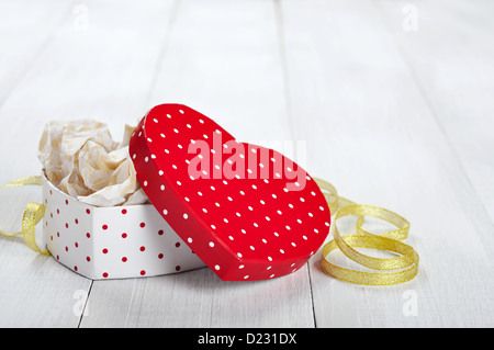 Confezione regalo a forma di cuore con nastro d'oro su sfondo di legno Foto Stock