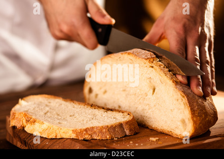 Il panettiere di crusca per affettare il pane su un tagliere Foto Stock