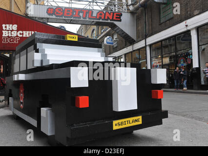 Londra, Regno Unito. Il 13 gennaio 2013. Un pixel taxi fuori su '8 Bit Lane' come parte della trasformazione di una strada nei pressi della Londra Brick Lane per il rilascio del film Disney 'Wreck-It Ralph'. Pixel di oggetti comprendente un pilastro casella e un taxi sono sparse intorno all'area che è stata con marchio "8 bit lane'. Foto Stock