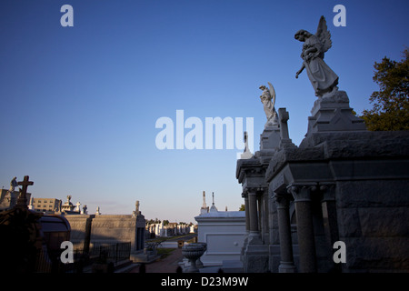 Statue e tombe in uno storico cimitero sopraelevato di New Orleans, Louisiana, sotto un cielo azzurro Foto Stock