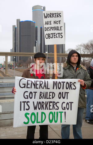 Detroit, Michigan - Auto i lavoratori si sono stretti al di fuori del North American International Auto Show, protestando in calo i salari e le condizioni di lavoro nel settore auto poiché il governo bailout dell'industria nel 2009. L'edificio in background è la sede centrale di General Motors. Foto Stock