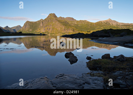 Picchi rocciosi e promontori si riflettono nelle tranquille acque del Fiordo Flakstadpollen, Lofoten, nel nord della Norvegia Foto Stock