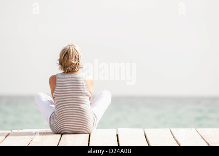 Spagna, Senior donna esercita sul pontile a mare Foto Stock