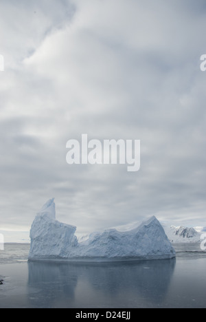 Iceberg contro il cielo nuvoloso e il ghiaccio. Foto Stock