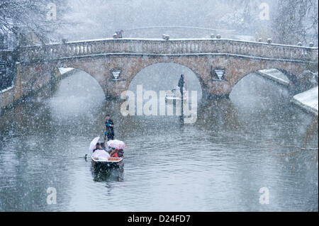 Cambridge Regno Unito 14 gennaio 2013. I turisti vanno punting sul fiume Cam in forte nevicata. Neve spessa caduto durante il pomeriggio in East Anglia e turisti goduto il paesaggio invernale lungo il dorso dei Collegi Universitari nonostante il meteo. Essi protetta sotto gli ombrelloni mentre i loro punt chauffeur diede loro un tour guidato. Foto Stock