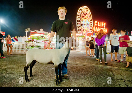 Ragazzo con una pecora e il parco dei divertimenti di corse al Maryland State Fair, Timonium MD Foto Stock