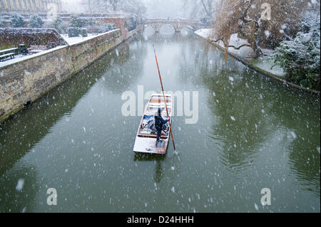 Cambridge Regno Unito 14 gennaio 2013. I turisti vanno punting sul fiume Cam in forte nevicata. Neve spessa caduto durante il pomeriggio in East Anglia e turisti goduto il paesaggio invernale lungo il dorso dei Collegi Universitari nonostante il meteo. Essi protetta sotto gli ombrelloni mentre i loro punt chauffeur diede loro un tour guidato. Foto Stock