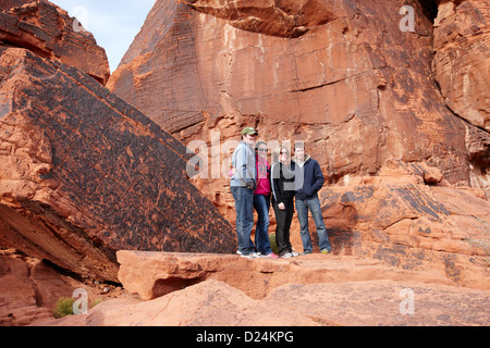 I turisti pongono di fronte petroglifi atlatl sul grande scoglio della valle del fuoco del parco statale nevada usa Foto Stock