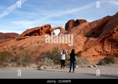 Due femmina turisti asiatici pongono e scattare foto di fronte arch rock in il parco della Valle di Fire State nevada usa Foto Stock