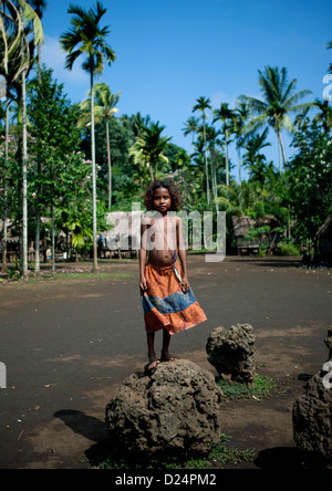 Ragazza in piedi sulla ex casa di filo pietre, Trobriand Isola, Papua Nuova Guinea Foto Stock