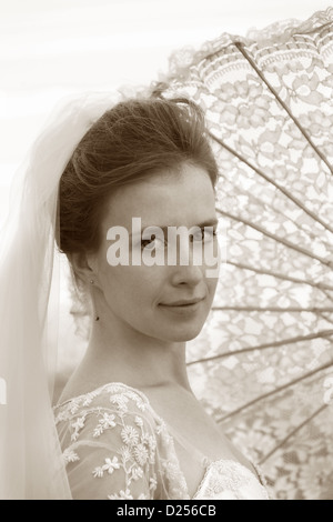 La bella sposa chiusa da un ombrello dal sole Foto Stock