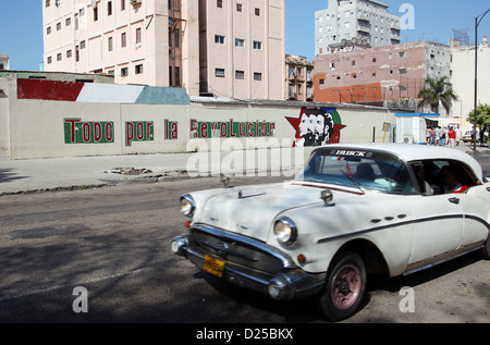 Un auto d'epoca rigidi passato una parete con la scritta 'Todo por la Revolucion' (lit. tutto per la rivoluzione) a l'Avana, Cuba, 21 gennaio 2012. Foto: Friso Gentsch Foto Stock