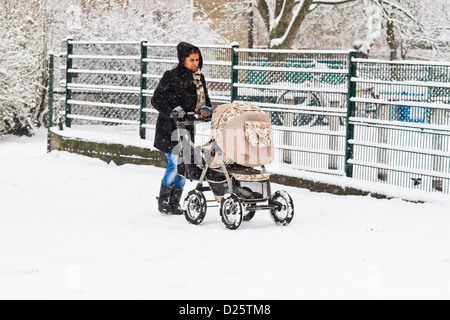 Una donna che spinge un buggy attraverso una nevicata a Berlino, Germania Foto Stock