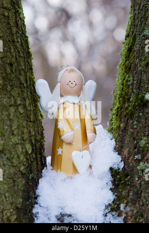 Un decorativo angelo di legno in un bosco innevato. Foto Stock