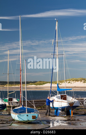 L'uomo preparando la sua barca tirata sulla sabbia a Beadnell Harbour, Northumberland, Inghilterra Foto Stock