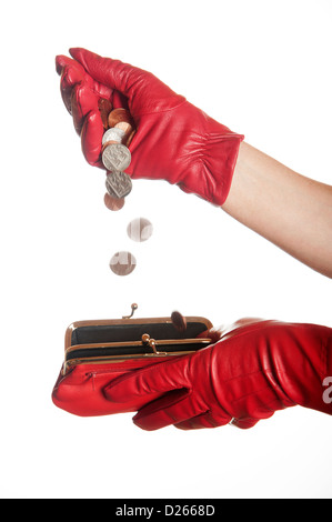 Versare il denaro in un portamonete rosso da un rosso guanti Foto Stock