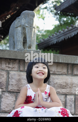 Abbastanza luminosa ragazza era seduto nella posizione del loto con pregando pongono Foto Stock