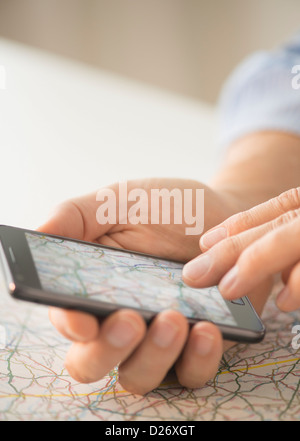 Close-up di mano utilizza lo smartphone su mappa Foto Stock