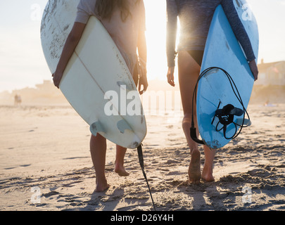 Stati Uniti d'America, nello Stato di New York, Rockaway Beach, due femmina surfers camminando sulla spiaggia Foto Stock