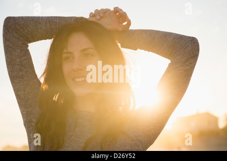 Stati Uniti d'America, nello Stato di New York, Rockaway Beach, donna sorridente al tramonto Foto Stock