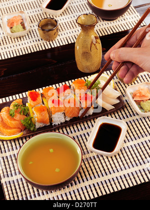 Primo piano di una mano di un uomo con bacchette di mangiare sushi al ristorante giapponese. Foto Stock