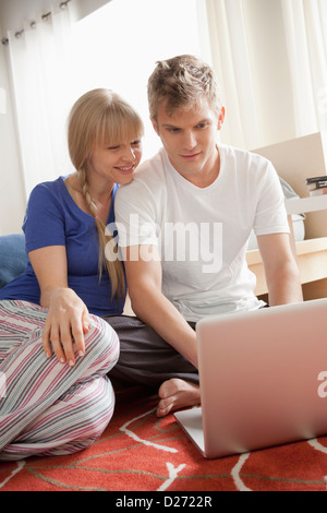 Giovane seduto sul pavimento con il computer portatile Foto Stock