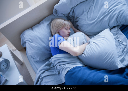 Vista in elevazione della donna che dorme e abbracciando cuscino Foto Stock