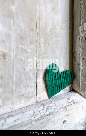 Verde buccia di cocco corteccia forma di cuore su un vecchio vestito di stracci porta in India Foto Stock