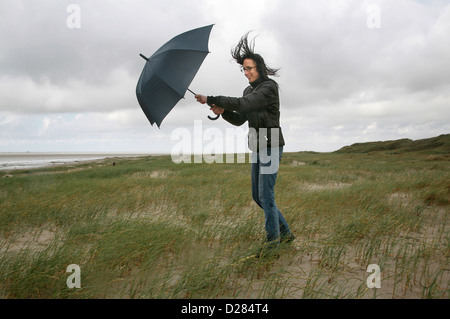Sankt Peter-Ording, Germania, una donna è camminare nel vento e pioggia sulla spiaggia Foto Stock