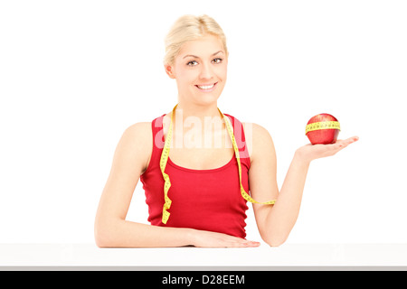 Sorridente giovane donna in possesso di un Apple e un nastro di misurazione, isolato su sfondo bianco Foto Stock