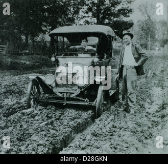 Uomo in piedi accanto alla donna in Ford Modello T auto sulla strada fangosa, agli inizi del novecento Foto Stock