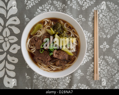 Home cotti Carni bovine Taiwanese noodle soup su una tabella grigia runner Foto Stock