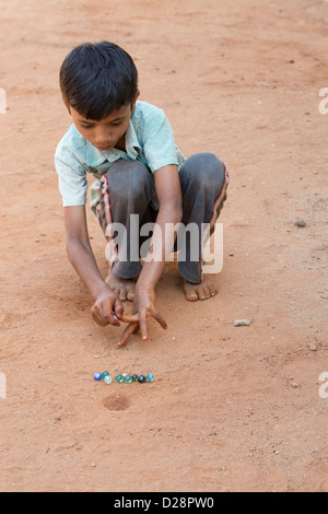 Ragazzo indiano la riproduzione di marmi in un territorio rurale villaggio indiano. Andhra Pradesh, India Foto Stock