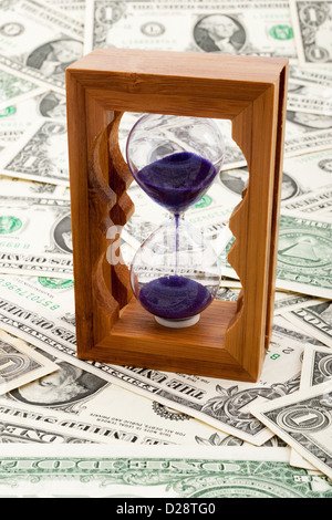Clessidra su uno strato di carta moneta Foto Stock