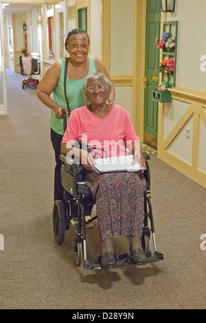 Accompagnatore spingendo anziani ipovedenti donna Foto Stock