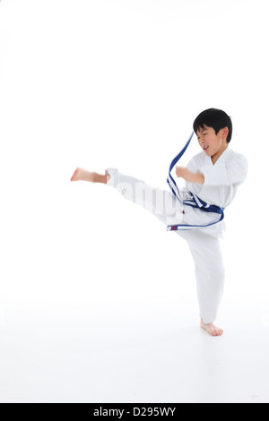 Giovane ragazzo asiatico con nastro blu, Karate calci in aria Foto Stock